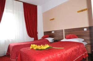 博托沙尼博托沙尼尊贵酒店的两张位于酒店客房的床,配有红色床单和黄色鲜花