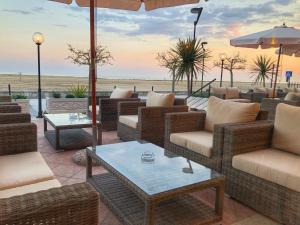 比比翁Hotel Karibe的露台配有柳条椅和桌子,背景为大海