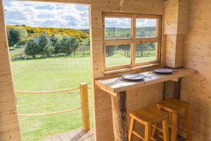 GlenfargLittle Lochan Lodge的小屋配有桌子、两张凳子和窗户