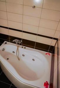 皮特什蒂Hotel Sorelo的浴室铺有黑色瓷砖,配有白色浴缸。