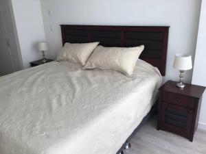 利马Moderno y funcional departamento Miraflorino的一间卧室配有一张带2个床头柜的大型白色床