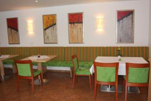 TimelkamHotel Sonnenhof的餐厅设有桌椅,墙上挂有绘画作品