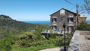 PorriEnglish Club in Corsica B&B的一座石头房子,位于一座小山上,背靠大海
