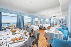 圣彼得港巡防舰酒店的餐厅设有白色的桌椅和窗户。