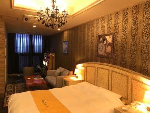 彦根市ホテルヴィラコスタ Adult Only 男塾ホテルグループ的一间卧室配有一张床、一张沙发和一个吊灯。