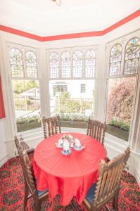 鲍内斯温德米尔Elim Bank Guest House的一间用餐室,配有红色的桌子、椅子和窗户
