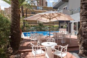 贝尼多姆 帕尔梅拉酒店的一个带桌椅和遮阳伞的庭院