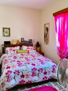 卡尔帕索斯Pangiotas Pencione的一间卧室配有一张带粉红色窗帘的床和风扇