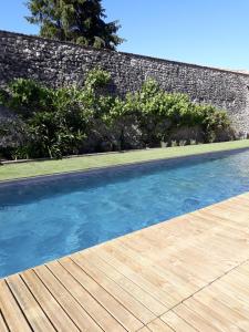 LamarqueLa Maison Reverdi的一个带木甲板的游泳池,旁边是墙壁