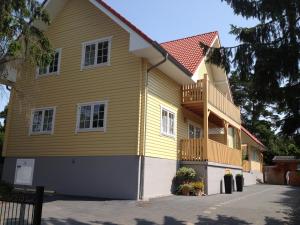 卢布明Haus Stoertebeker Appartements - Hotel Garni, Seebad Lubmin的黄色的房屋设有门廊和阳台