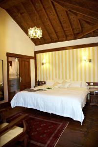 伊科德洛斯维诺斯埃姆布勒玛提卡圣奥古斯丁酒店的卧室配有一张白色大床和木制天花板