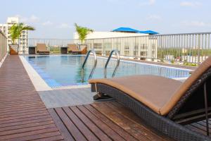 科钦JVK Park Hotel的阳台的游泳池及躺椅
