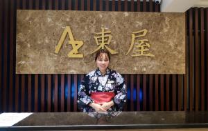 海防Azumaya Hotel Hai Phong的站在标牌前的柜台上的女人