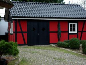 格罗斯齐克Landhaus Uhlenhof 4的红黑谷仓,有白色的窗户