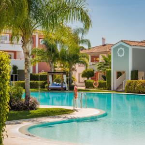 EsteponaCortijo Del Mar Resort的棕榈树度假村的游泳池以及大楼