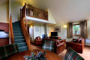 阿维莫尔Macdonald Woodland Lodges at Macdonald Aviemore Resort的客厅设有楼梯和桌椅