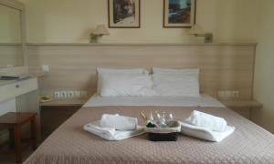 卡拉马基亚历山德罗斯公寓酒店的一张带两条毛巾和两杯眼镜的床