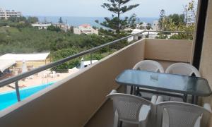 卡拉马基亚历山德罗斯公寓酒店的一个带桌椅的阳台和一个游泳池