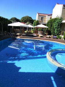 卡图亚该亚Naiades Villas的一个带椅子和遮阳伞的大型蓝色游泳池