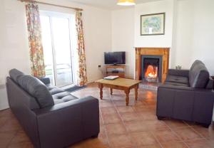 巴利巴宁Ballybunion Holiday Cottages No 7的客厅设有两张沙发和一个壁炉