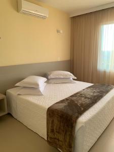 隆德里纳Dunamys Hotel Londrina的卧室配有一张带白色床单和枕头的大床。