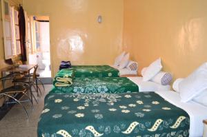 瓦尔扎扎特Hotel Atlas Ouarzazate的配有绿床单的酒店客房的两张床