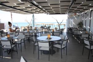 新马尔马拉斯Meliton Inn Hotel & Suites by the beach的餐厅设有桌椅,以大海为背景