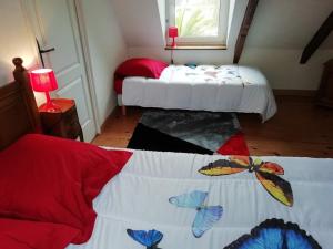 BégardLa Peupleraie的一间卧室设有两张床和一张带蝴蝶床单的床