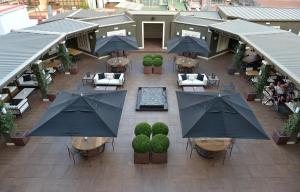 巴塞罗那格兰大道酒店的享有带桌子和遮阳伞的天井的顶部景致。