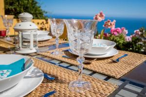贝纳尔马德纳Villa La Tuna的桌子上摆着玻璃杯和盘子,与大海一同