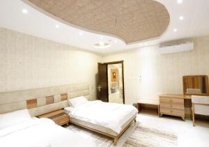 塔伊夫Four Seasons Suites的一间卧室配有两张床、一张桌子和一张四柱床。