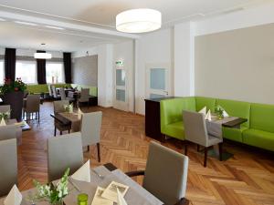 洛尔施Hotel Karolinger Hof的一间设有绿色家具和桌椅的餐厅