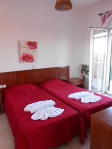 斯达林Marie的一间卧室配有两张带红色床单和白色毛巾的床