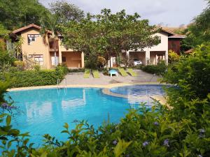 普拉亚埃尔莫萨Condominio Villa Hermosa的一个带椅子和树木的度假村游泳池
