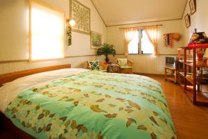 轻井泽ペンションカパルア軽井沢的一间卧室配有一张大床和色彩缤纷的毯子