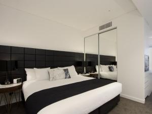 悉尼查茨伍德希尔卡里套房公寓式酒店的一间卧室设有一张大床和一个大镜子
