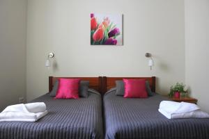 波德古任邱妮科酒店的卧室内的两张床和粉红色枕头