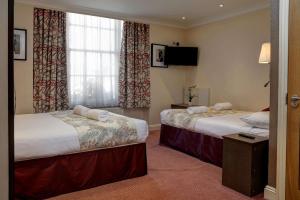 伦敦Best Western Buckingham Palace Rd的酒店客房设有两张床和电视。