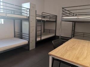 珀斯Quokka Backpackers Hostel Perth - note - Valid passport required to check in的客房设有三张双层床和一张桌子。
