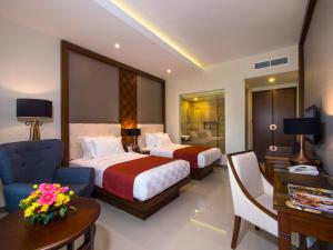 马格朗Puri Asri Hotel & Resort的酒店客房配有两张床、一把椅子和一张书桌