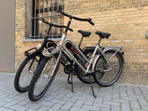 吕伐登Alibi Hostel Leeuwarden的两辆自行车停在砖墙旁边