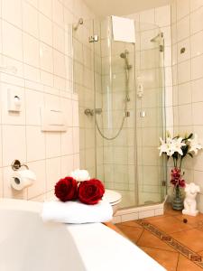 谬克Landhotel Restaurant Gärtner的带淋浴的浴室和毛巾上的红玫瑰