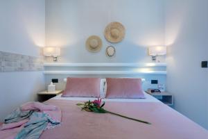 普拉塔尼亚斯Sonio Beach - Que Bella Collection的一张带粉红色枕头的床和一朵花