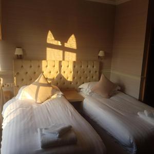 ArmathwaiteFox and Pheasant Inn的酒店的客房内设有两张床,透过窗户享有阳光。