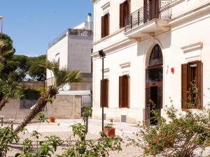 莱切Lobby Collective Hostel - Lecce的一座白色的建筑,前面有棕榈树