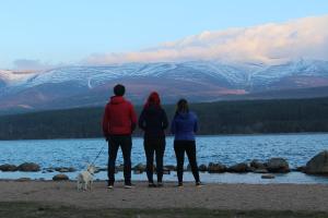 Loch MorlichCairngorm Lodge Youth Hostel的三人与狗一起站在海滩上