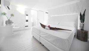 里米尼Q酒店的白色卧室配有白色床单和白色大床