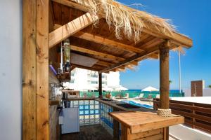 普罗塔拉斯Seafront Protaras Villas的游泳池旁的带草屋顶的酒吧