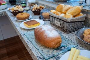 波苏斯-迪卡尔达斯Hotel Pousada Beija Flor的盘子上带面包和糕点的桌子