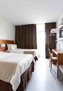 内乌肯埃拉杜拉套房酒店的酒店客房设有两张床、一张桌子和一张书桌。